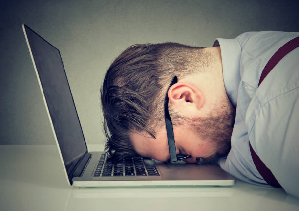 Image of man with his head on a keyboard seeming frustrated